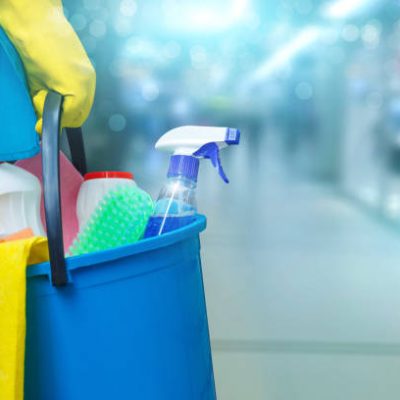 Cleaning lady with a bucket and cleaning products on blurred background .